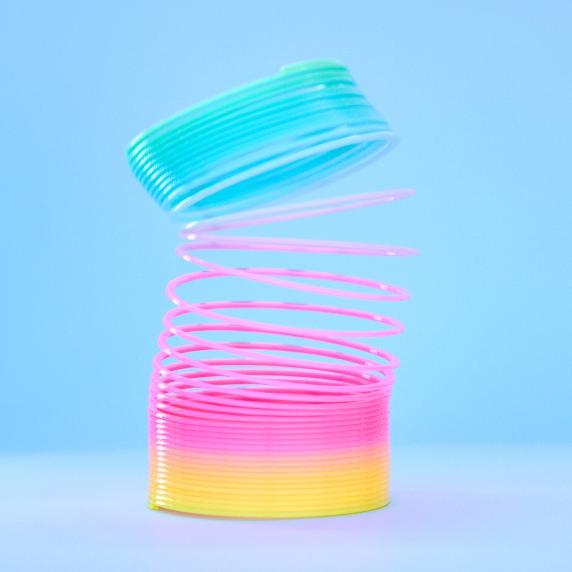 Closeup of a colourful flexible plastic rainbow slinky toy in stretched out motion isolated against