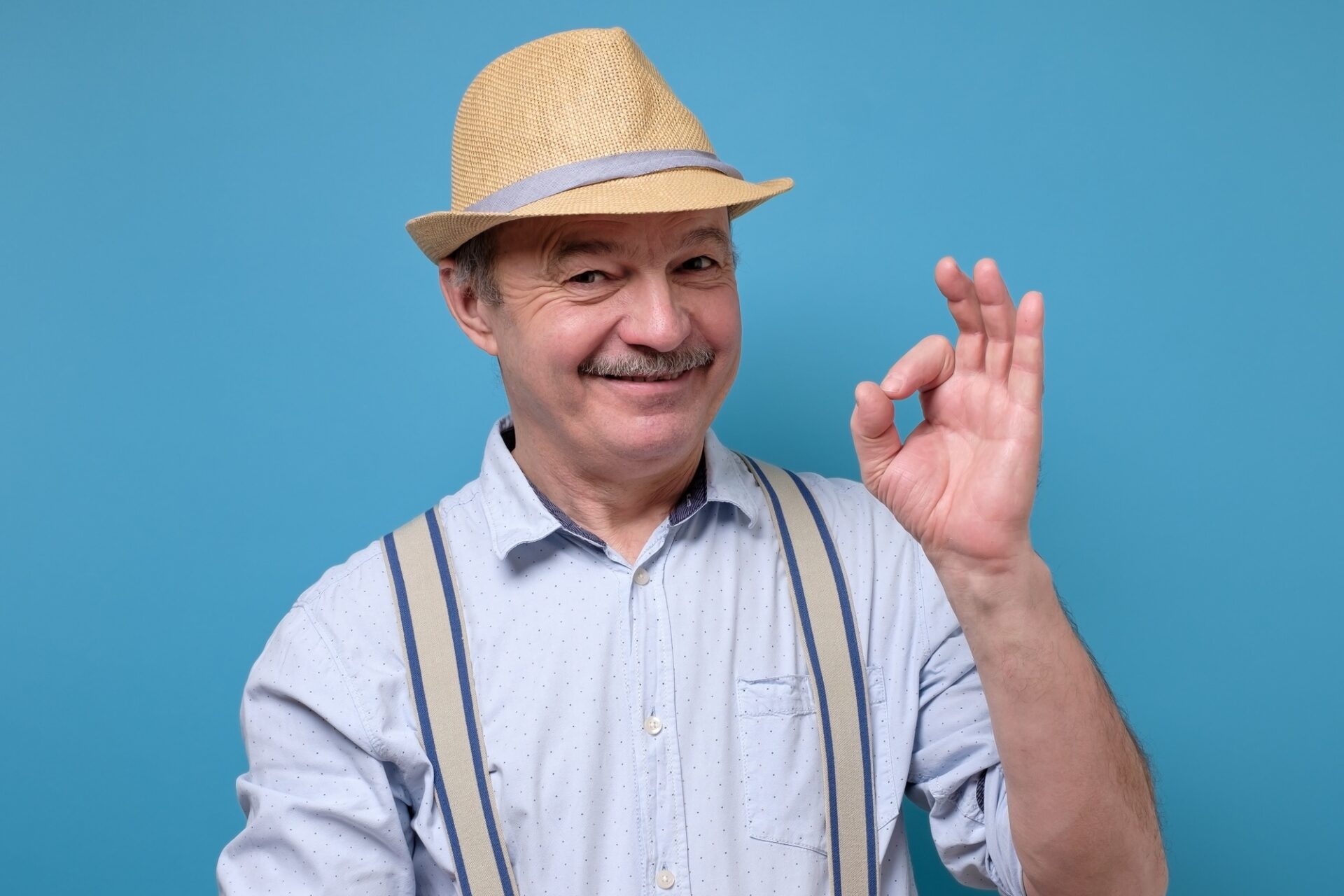Senior spanish man showing OK sign approving choice.
